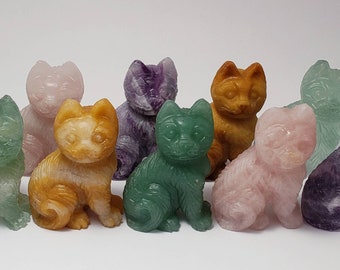 May include: A collection of ten small, carved cat figurines made of various semi-precious stones. The cats are in different colors, including green, pink, purple, and brown.