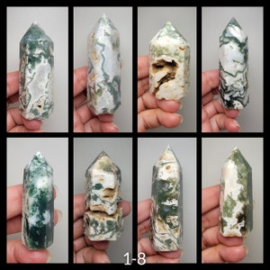 May include: Eight moss agate crystal points, each with unique patterns of green, white, and tan. The crystals are displayed against a neutral background, showcasing their natural beauty and variations in texture and color.