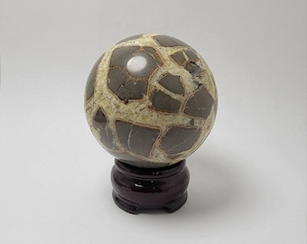 May include: A brown and white geode sphere on a dark wood stand. The sphere is polished and has a natural, organic pattern.