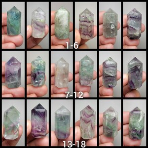 May include: 18 green, purple, and white fluorite crystal points, each approximately 2 inches long, arranged in three rows of six. The points are displayed on a white background.