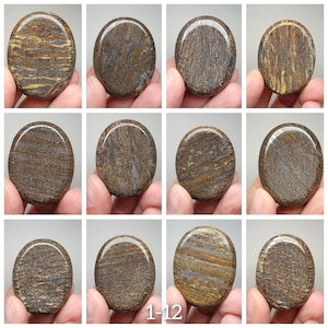 May include: Twelve smooth, oval-shaped stones with a brown and blue marbled pattern. The stones are arranged in four rows of three. The stones are all approximately the same size and shape.