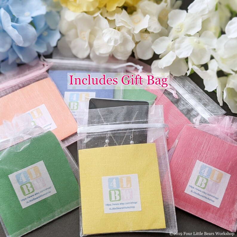 Pu&ograve; includere: Primo piano di cinque piccole buste regalo in tessuto trasparente. Ogni busta contiene un piccolo biglietto con il testo "4 Little Bears Workshop" e un indirizzo del sito web. Le buste sono disposte in fila, con il testo "Includes Gift Bag" scritto in grandi lettere sopra.