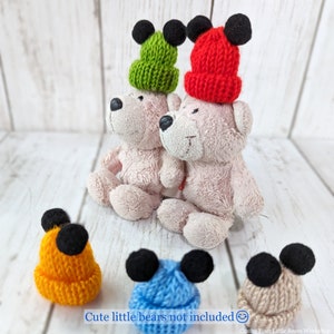 Pu&ograve; includere: Quattro cappelli di lana con orecchie di Topolino. I cappelli sono verde, rosso, arancione e blu.  "Cute little bears not included." &egrave; scritto sotto i cappelli.