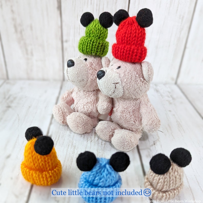 Pu&ograve; includere: Quattro cappelli di lana con orecchie di Topolino. I cappelli sono verde, rosso, arancione e blu.  "Cute little bears not included." &egrave; scritto sotto i cappelli.