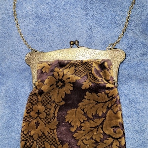 Peut inclure: Un sac &agrave; main vintage en cha&icirc;ne dor&eacute;e avec une doublure en tissu &agrave; motif floral brun et or. Le sac &agrave; main a un fermoir argent&eacute; et une bordure &agrave; franges.