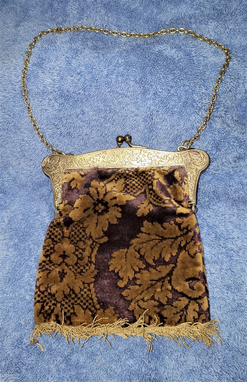 Peut inclure: Un sac &agrave; main vintage en cha&icirc;ne dor&eacute;e avec une doublure en tissu &agrave; motif floral brun et or. Le sac &agrave; main a un fermoir argent&eacute; et une bordure &agrave; franges.