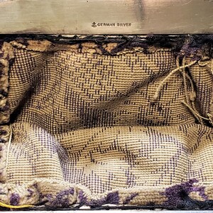 Peut inclure: Un sac &agrave; main argent&eacute; avec une bandouli&egrave;re en cha&icirc;ne et une doublure en tissu. Le sac &agrave; main a une fermeture &agrave; fermoir et les mots "German Silver" sont estampill&eacute;s &agrave; l'int&eacute;rieur.