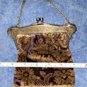 Peut inclure: Un sac &agrave; main vintage en argent et or avec une pochette en velours marron &agrave; motif floral dor&eacute;. La pochette est orn&eacute;e d'une frange.