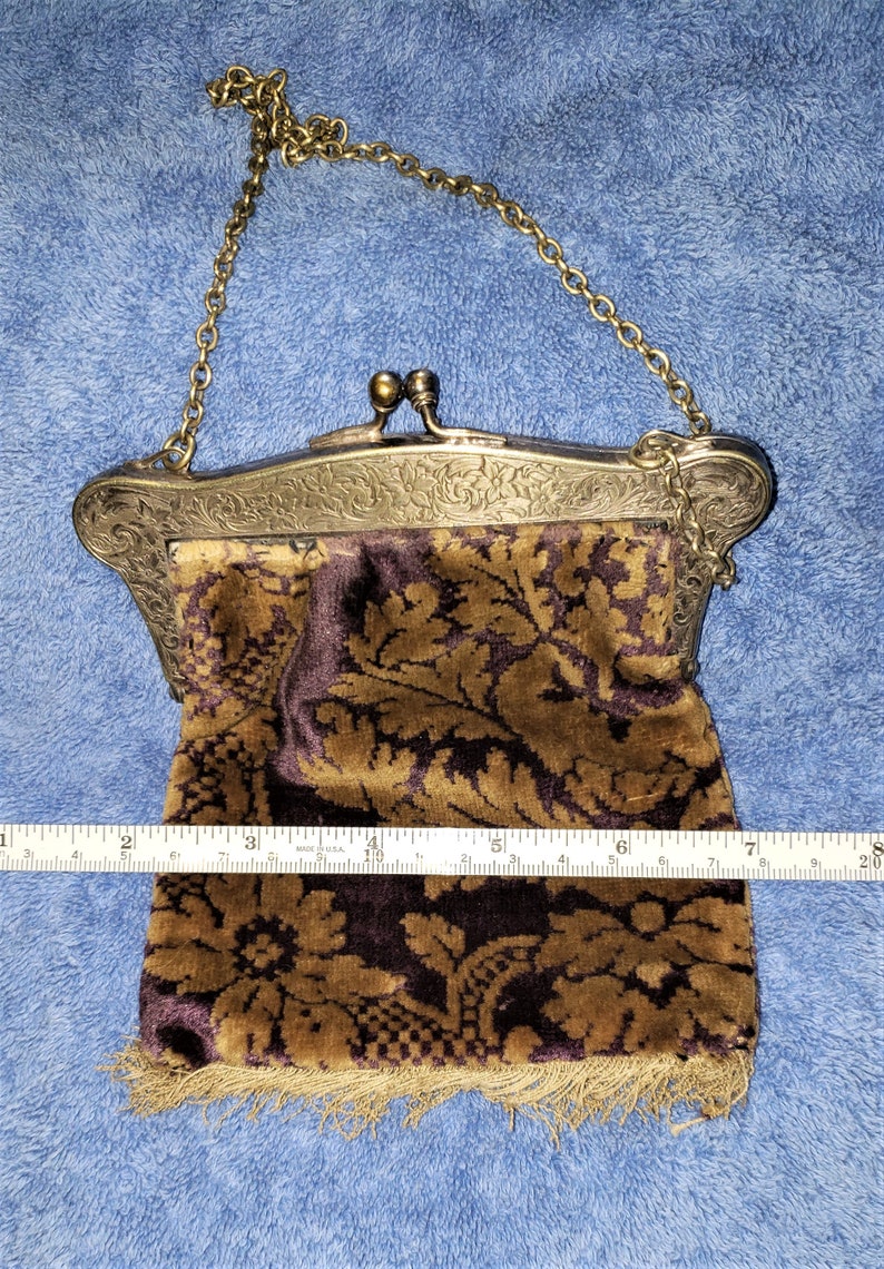 Peut inclure: Un sac &agrave; main vintage en argent et or avec une pochette en velours marron &agrave; motif floral dor&eacute;. La pochette est orn&eacute;e d'une frange.