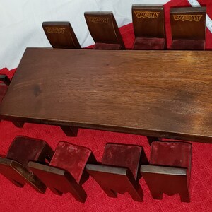 Puede incluir: Un juego de comedor de madera con seis sillas. La mesa es marrón y las sillas tienen asientos de terciopelo rojo. Las sillas tienen un diseño tallado en el respaldo.