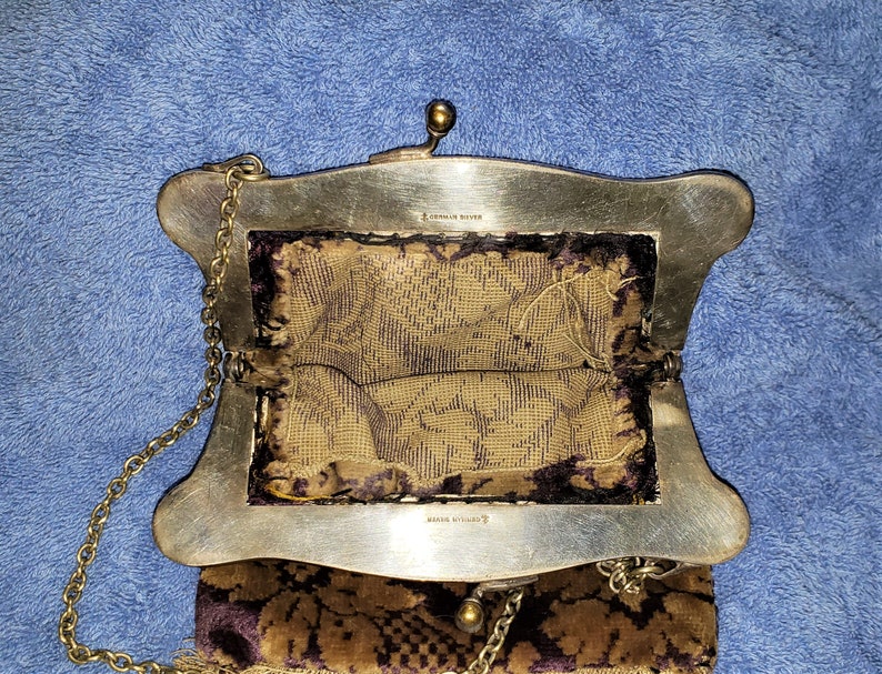 Peut inclure: Un sac &agrave; main vintage en argent et or avec une bandouli&egrave;re en cha&icirc;ne et une doublure &agrave; motif floral. Le sac porte les inscriptions "AMERICAN SILVER" et "MADE IN ENGLAND" &agrave; l'int&eacute;rieur.
