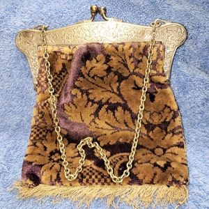Peut inclure: Un sac &agrave; main vintage en m&eacute;tal dor&eacute; avec un motif floral orn&eacute; et une doublure en velours brun. Le sac &agrave; main a une bandouli&egrave;re en cha&icirc;ne et une bordure en frange.