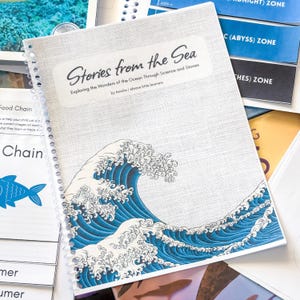 May include: A spiral-bound educational workbook titled Stories from the Sea: Exploring the Wonders of the Ocean Through Science and Stories by Amelia | ebrave.little.learners, featuring a large blue and white graphic of a crashing ocean wave.