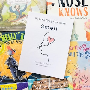May include: A collection of children's books with colorful illustrations. The central book cover features the word "Smell" with a line drawing of a nose and a heart. Other book titles include "Nose Knows" and "What If You Had an Animal Nose?"
