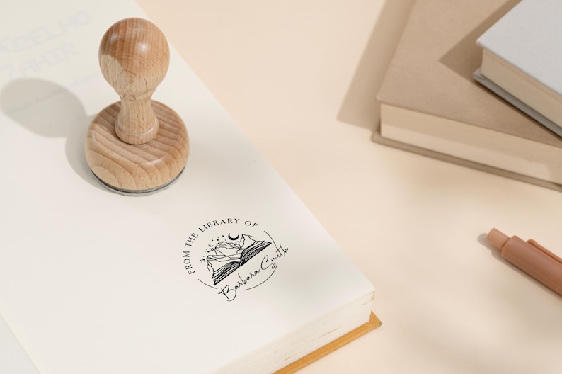 May include: A wooden stamp with a circular design featuring a book with mountains and a crescent moon. The text "From the Library of Barbara Smith" is printed around the design.