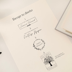 May include: A sheet of paper with four different black ink stamp designs for books. The text "Escoge tu dise&ntilde;o" is at the top. Designs include names and the words "Ex Libris". A pair of glasses is in the lower left corner.