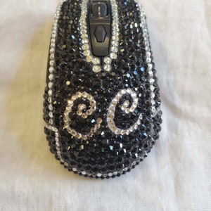 May include: A black computer mouse covered in black and silver rhinestones. The rhinestones are arranged in a swirling pattern.