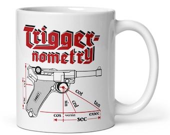 May include: White ceramic mug featuring the words "Triggernometry" in red gothic lettering above a detailed black and white illustration of a handgun with trigonometric labels. The mug has a white handle.