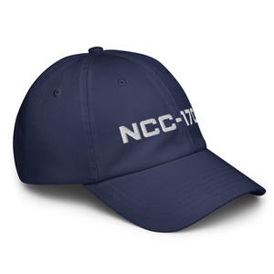 Peut inclure: Une casquette de baseball bleu marine avec le texte brodé en blanc NCC-1701 sur le panneau avant. La casquette présente une calotte structurée, une visière incurvée et un bouton au sommet. Le tissu semble être un sergé de coton lisse et uni.
