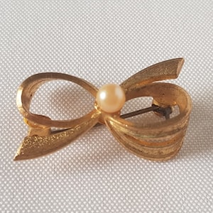 Vintage jewelry brooch, in bow shape with faux pearl, in gold tone, 50s-60s