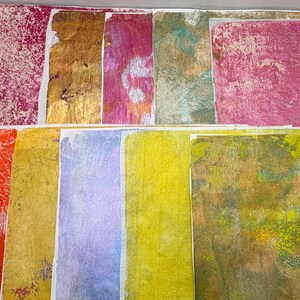 May include: A collection of colorful, textured paper squares. The colors include shades of red, gold, pink, green, yellow, and purple. The textures vary from smooth to heavily patterned, creating a collage-like appearance.