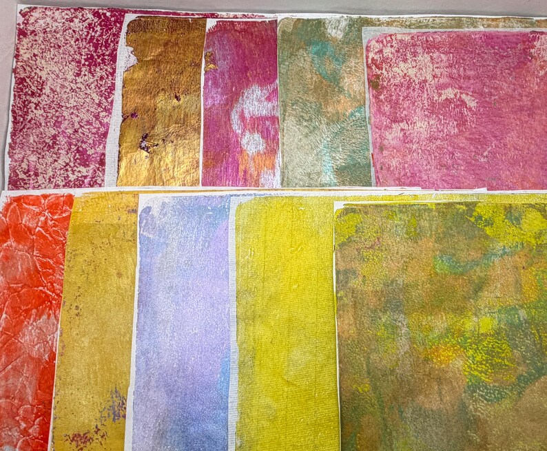 May include: A collection of colorful, textured paper squares. The colors include shades of red, gold, pink, green, yellow, and purple. The textures vary from smooth to heavily patterned, creating a collage-like appearance.