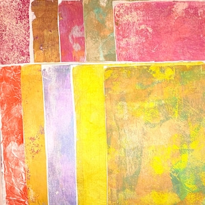 May include: A collection of colorful, textured paper sheets. The palette includes shades of red, orange, yellow, purple, and green. The papers have a variety of patterns and textures, with some appearing crinkled or layered. The overall effect is artistic and vibrant.