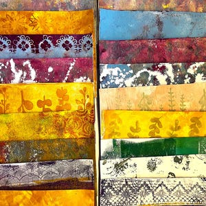 Può includere: Una collezione di strisce di carta colorate e strutturate disposte verticalmente. Le strisce presentano vari motivi e colori, tra cui disegni floreali, motivi a pizzo e texture astratte. I colori includono giallo, blu, viola e verde.