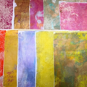 May include: An assortment of colorful, textured paper sheets. The papers display a variety of colors, including red, gold, purple, and yellow, with unique patterns and textures. Some sheets have a mottled appearance, while others have a more uniform color.