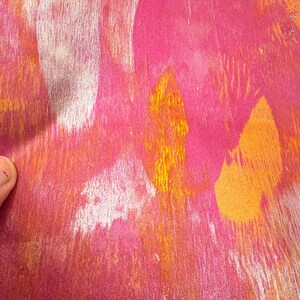 May include: Abstract artwork with a textured appearance. The piece features a blend of vibrant colors, including shades of pink, orange, and white. The brushstrokes create a dynamic and expressive composition, suggesting a modern art style.
