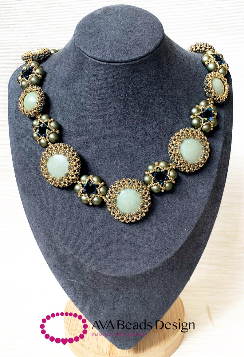 May include: A green and gold beaded necklace with round, light green stones. The necklace is displayed on a gray mannequin bust.