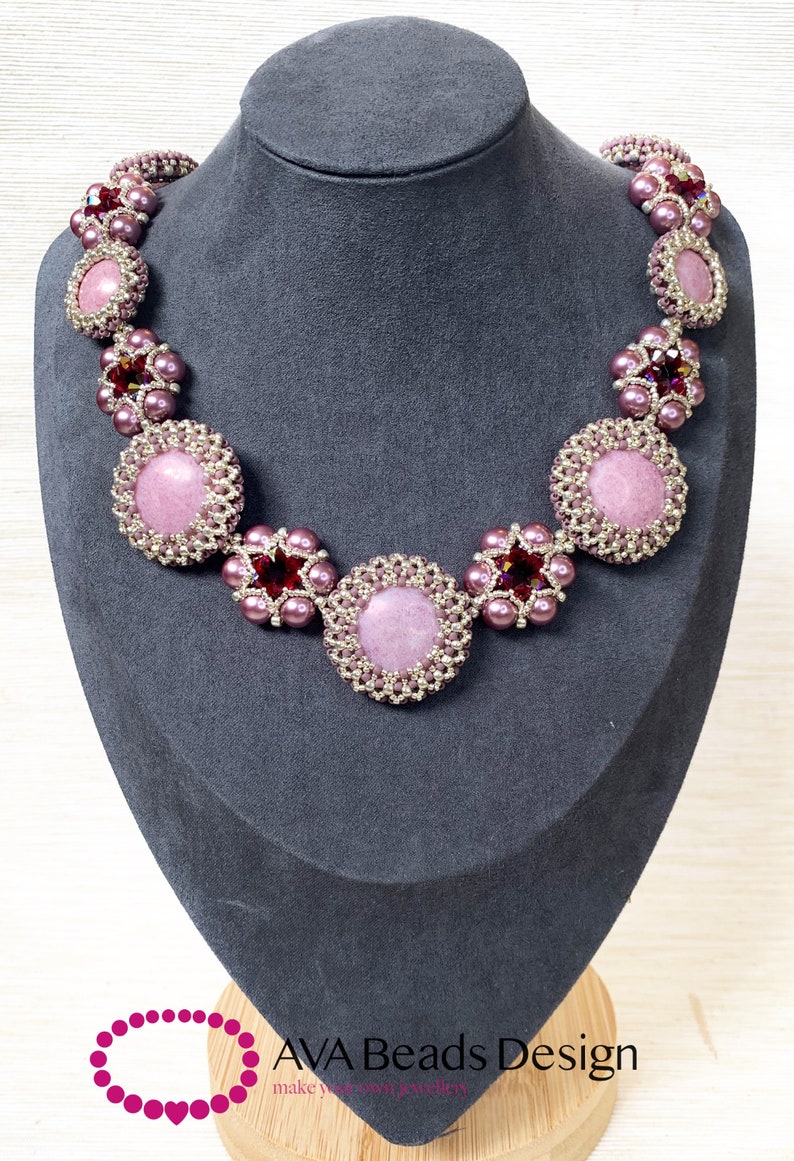 May include: A pink and silver beaded necklace with a pink stone centerpiece. The necklace is displayed on a gray mannequin bust. The text "AVA Beads Design" is visible at the bottom of the image.