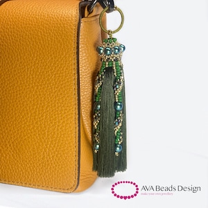 May include: A green and gold beaded tassel keychain with a crown-shaped top. The tassel is attached to a brown leather handbag.