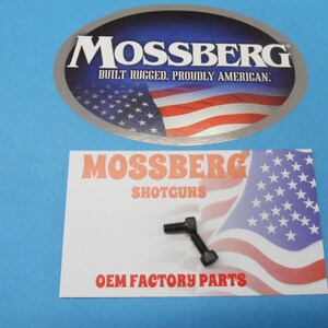 May include: A close-up of a small, black metal screw with a 90-degree bend. The screw is on a white card with the text "Mossberg Shotguns OEM Factory Parts" and an American flag graphic.