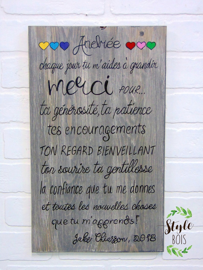 Puede incluir: Un letrero de madera con fondo gris y texto negro. El letrero dice "Aneli&eacute;e" con corazones coloridos sobre el texto. El texto contin&uacute;a, "Chaque jour tu m'aides &agrave; grandir merci pour... ta g&eacute;n&eacute;rosit&eacute;, ta patience tes encouragements TON REGARD BIENVEILLANT ton sourire ta gentillesse la confiance que tu me donnes et toutes les nouvelles choses que tu m'apprends! Jake Chiasson, 2018". El letrero tambi&eacute;n tiene un dise&ntilde;o de hoja verde en la esquina inferior derecha con el texto "Style Bois".