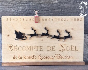 May include: Wooden Christmas countdown calendar featuring a reindeer and Santa Claus design. The calendar has numbers 1 to 25 and the text "DÉCOMPTE DE NOËL de la famille Levesque/Boucher".