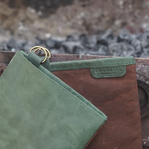May include: A green leather pouch with a brown canvas pouch inside. The canvas pouch has a brown leather label with the text "POHVALIN" on it.