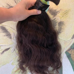 May include: A dark brown wavy hair extension with a black tag that says "Indian Hair".