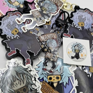 Puede incluir: Una colección de pegatinas, llaveros y un botón de estilo anime con un personaje de pelo azul claro, atuendo negro y máscara amarilla. Algunos artículos tienen el texto "HANDY MEN" y "SHIGARAKI".
