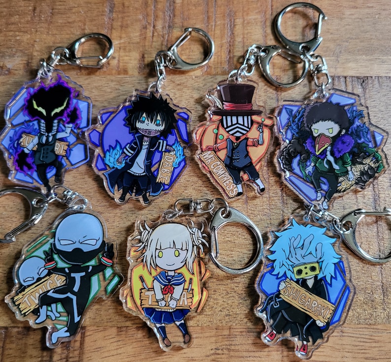 May include: Set of 8 anime character keychains featuring characters from the My Hero Academia series. The keychains are made of clear acrylic and feature colorful illustrations of the characters. The characters include: Twice, Shigaraki, Dabi, Mr. Compress, Toga, and others.