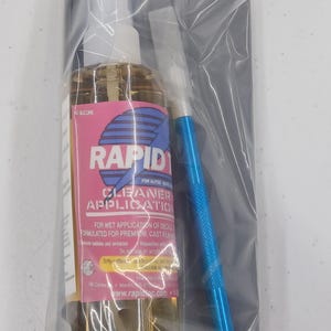 May include: A clear plastic spray bottle labeled Rapid Tac Cleaner Application with a pink label, a blue metal craft knife with a silver blade, and a black rectangular squeegee, all sealed together inside a clear plastic bag for decal application.