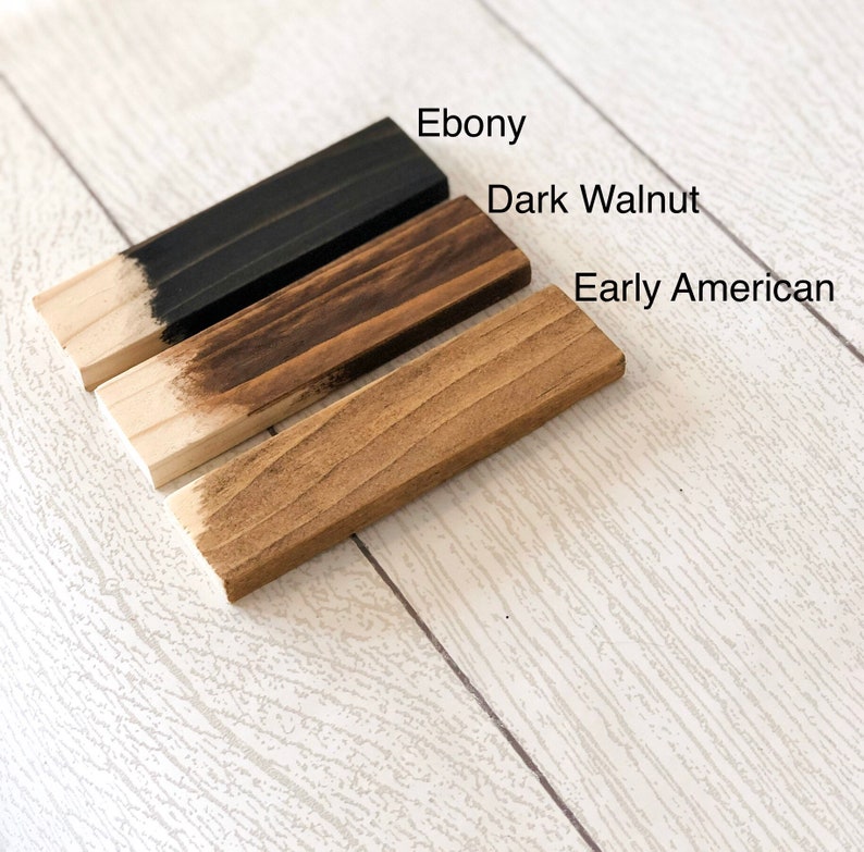 May include: Three wood samples stained in different colors: Ebony, Dark Walnut, and Early American. The samples are arranged from darkest to lightest.