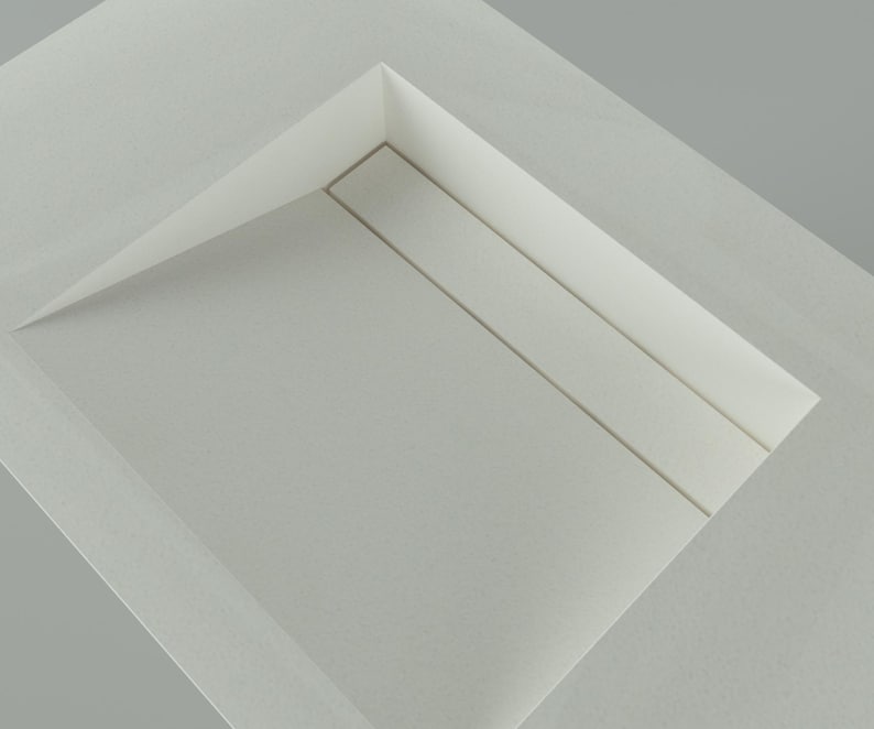 May include: A minimalist, abstract composition featuring a white, folded paper structure. The design incorporates a recessed rectangular area with subtle linear details, creating a sense of depth and shadow play. The overall aesthetic is clean and modern.
