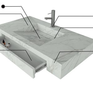 May include: A modern white marble bathroom vanity with an integrated ramp sink, seamless mitered edge, and customizable faucet holes. Features a removable drain and water edge design. Includes a drawer to modify with add-ons.
