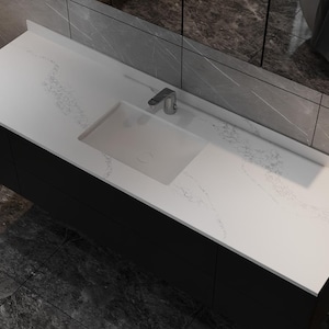 May include: A modern bathroom vanity with a white countertop featuring subtle gray veining. The vanity has a rectangular, integrated sink and a chrome faucet. The base is a dark, solid color, and the design is sleek and contemporary.