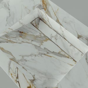 May include: A close-up of several white marble tiles with gray and gold veining. The tiles are arranged at different angles, showcasing the natural patterns and textures of the stone. The overall effect is a display of elegant, natural stone.