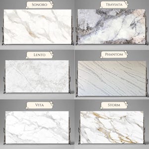 May include: A display of twelve rectangular stone slabs with various marble patterns. Each slab is labeled with a name, including "Ardorse," "Sondro," and "Panda." The slabs are mounted on metal stands, showcasing the different designs.