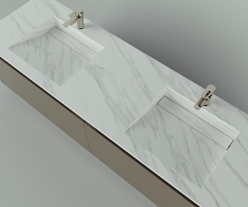 May include: A modern bathroom vanity with two integrated sinks and chrome faucets. The countertop features a white marble pattern, and the cabinet has a neutral, light brown finish. The design is sleek and minimalist, suitable for contemporary bathrooms.