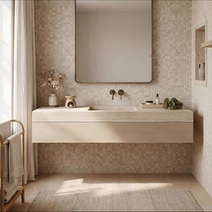 Puede incluir: Un mueble de ba&ntilde;o flotante de madera clara con lavabo integrado, un espejo rectangular de esquinas redondeadas y grifos de pared en bronce. El mueble sostiene un jarr&oacute;n de cer&aacute;mica con flores secas, un calentador de velas y una bandeja.