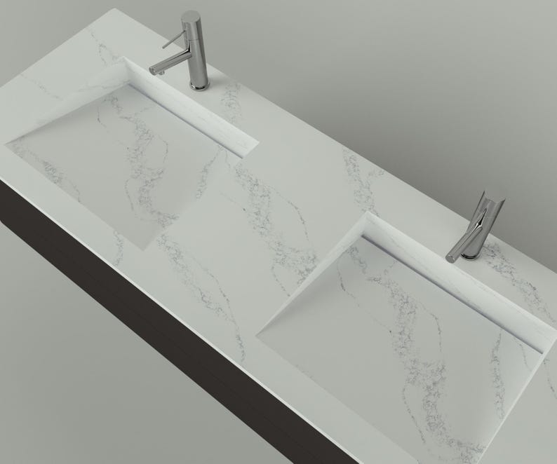 May include: A modern, double-sink vanity with a white marble-look countertop. The countertop features two rectangular integrated sinks and two chrome faucets. The vanity has a dark brown base and is set against a light gray background.